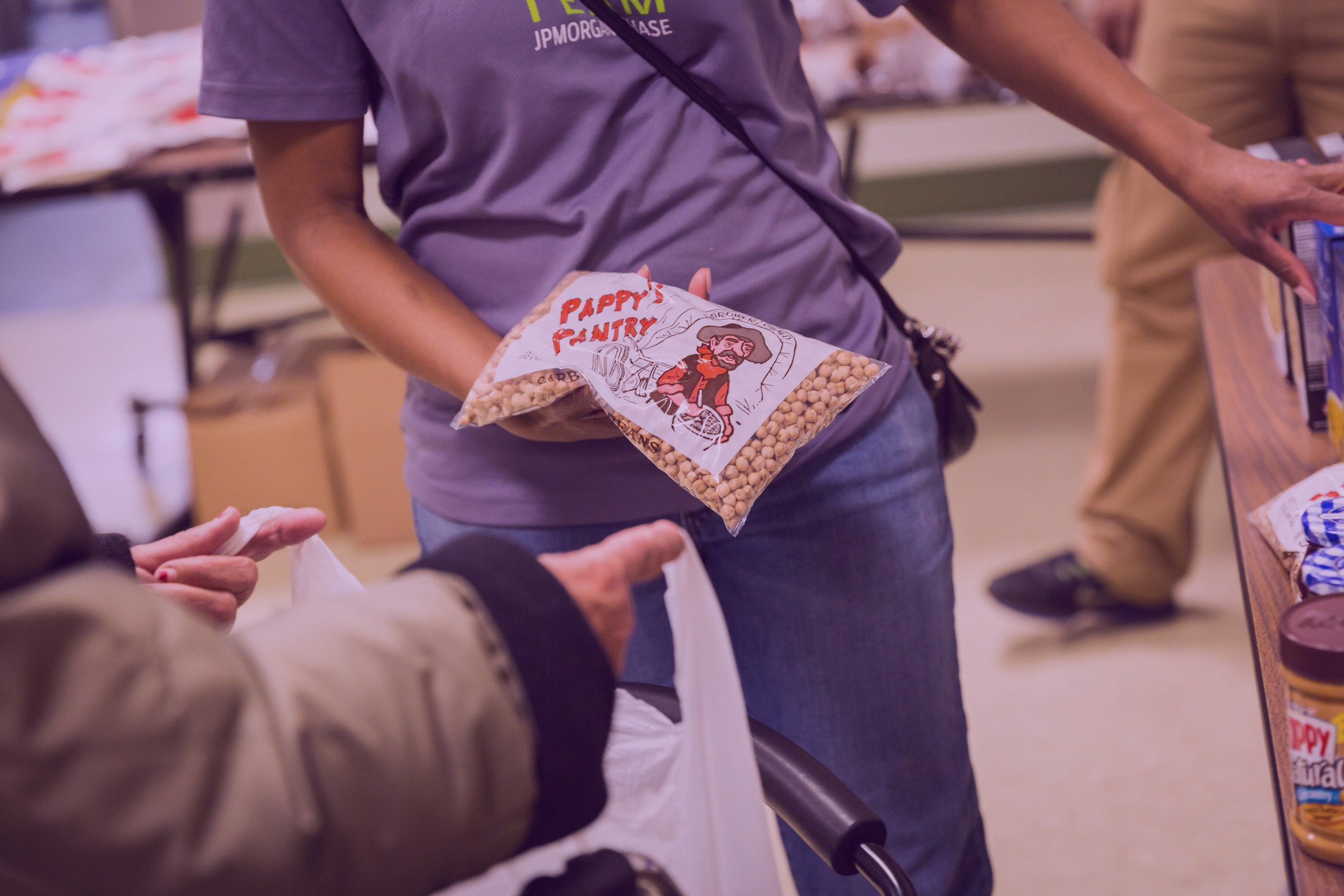 A food pantry volunteer handing out a package of beans